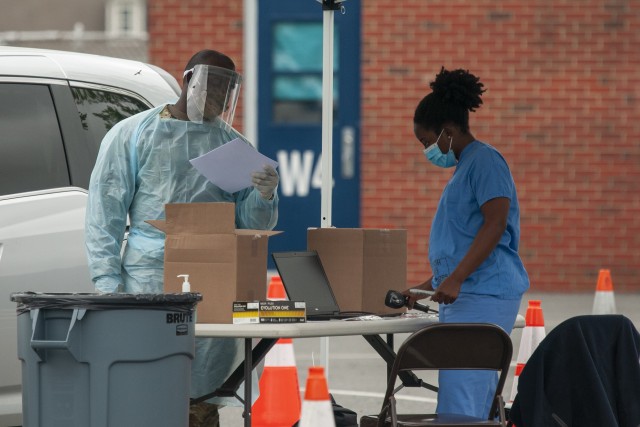 Pfc. Michael Brown, a military policeman, and Spc. Ashley Jacobs, a combat medic, wear personal protective equipment during a drive-thru coronavirus testing mission at W.T. Chipman Middle School in Harrington, Del., May 28, 2020. About 25 members of the Delaware National Guard supported the saliva-based testing of roughly 585 people at the downstate location. 