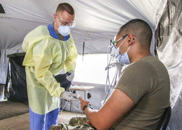 Spc. Jacob Jones, a healthcare specialist at Kleber Army Health Clinic, screens a Soldier for COVID-19 symptoms at the clinic’s temporary COVID-19 facility, May 27.