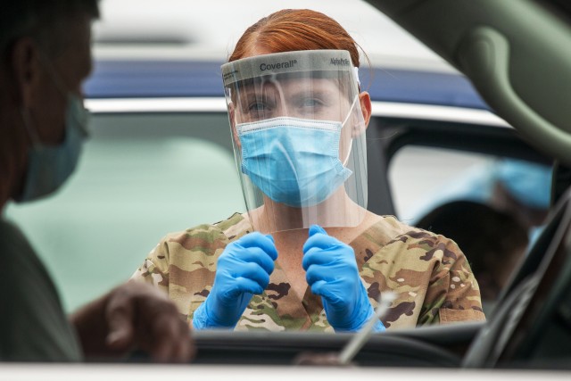Pfc. Kelly Buterbaugh, a combat medic with the Delaware Army National Guard, gives instructions to a motorist during a drive-thru coronavirus testing mission at the University of Delaware&#39;s Science, Technology and Advanced Research Campus in Newark, Del., May 29, 2020. About 25 Soldiers and airmen with the Delaware National Guard supported the saliva-based testing of roughly 400 people at the STAR Campus location.  