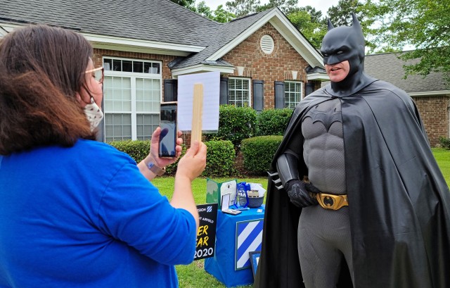 Fort Stewart’s Army Community Service support assistant Michelle Glenn, introduces Sgt. Anthony Licata, a trumpet player assigned to the 3rd Infantry Division Band who is donning a Batman costume, via a simulcast that was live-streamed for the...