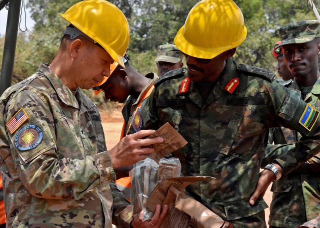 U.S. Army Brig. Gen. Lapthe C. Flora, deputy commanding general for U.S. Army Africa, left, shows Rwanda Defence Force Brig. Gen. John Baptist Ngiruwonsanga, exercise co-director, center, the choices inside a meal ready to eat (MRE) during a visit to exercise participants at the Exercise Shared Accord 2019 engineering field training exercise site, Rwanda Military Academy, Gako, Rwanda, August 18, 2019. Shared Accord 2019, which runs Aug. 14- 28, is focused on bringing together U.S. and Rwandan forces, African partner militaries, allies and international organizations to increase readiness, interoperability, and partnership building between participating nations for peacekeeping operations in the Central African Republic. (U.S Air National Guard photo by Senior Master Sgt. Janeen Miller)