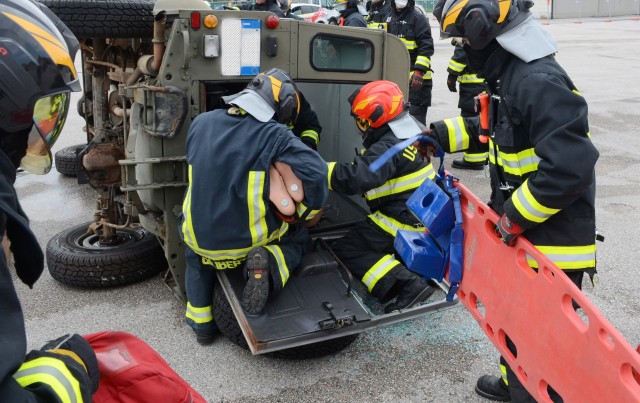 Firefighters from U.S. Army Garrison Italy Emergency Services directorate, take actions to safely treat and remove training mannequins from a vehicle during one of the extrication exercises on Caserma Ederle June 10, 2020. After the removal of a section of the vehicle, the long spine board (on the right) is used to extract the casualty.