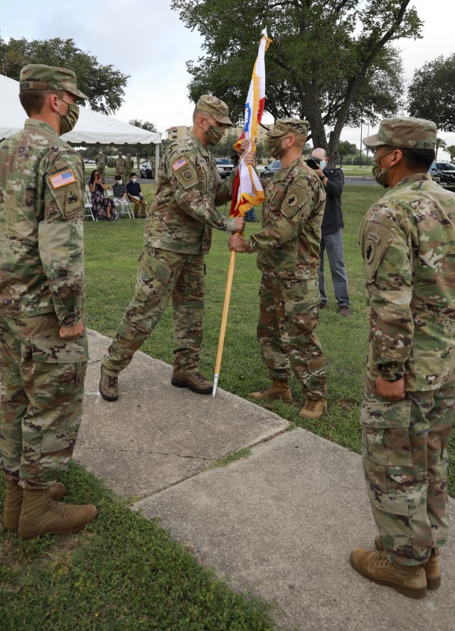 Maj. Gen. Daniel R. Walrath, U.S. Army South commanding general, passes the unit colors to Lt. Col. Mark A. Katz, Headquarters and Headquarters Battalion incoming commander, to formally represent the transfer of authority and responsibility during a change of command ceremony on June 16 at Joint Base San Antonio-Fort Sam Houston.