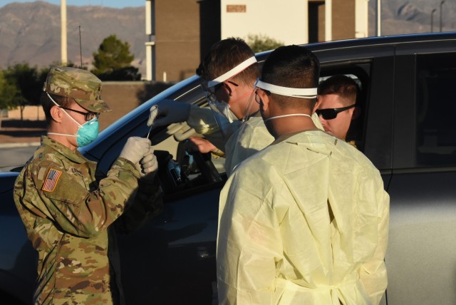 Soldiers of the 1st Armored Division, Combat Aviation Brigade, donning their Personal Protective Equipment, perform drive thru COVID-19 testing on Soldiers in order to ensure their medical readiness.