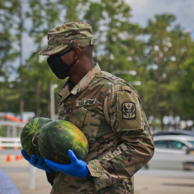 North Carolina Army National Guard Sgt. Ethan Terry, assigned to 2-130th Airfield Operations Battalion, loads watermelons into a vehicle alongside volunteers from Team Rubicon, a veteran disaster relief service organization, Action Pathways, a...