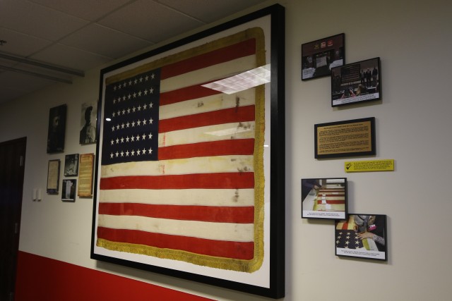 The colors of the 10th Mountain Division Artillery in WWII hang from the wall in the conference room of Ruffner Hall as of June 19, 2020 on Fort Drum, N.Y. They were restored, cleaned, and placed in a 5 - foot by 7 - foot frame, flanked by plaques telling the flag and the unit’s history. (U.S. Army photo by Pfc. Anastasia Rakowsky)