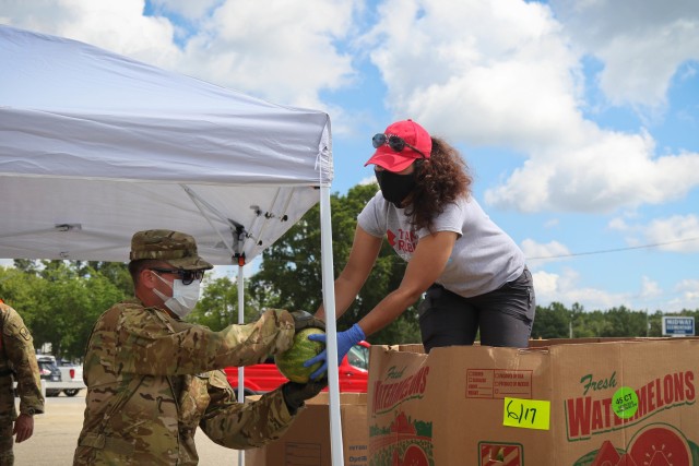 North Carolina Army National Guard Chief Warrant 2 Greg Preston (left) of the 1-130th Attack Reconnaissance Battalion works along side Claudia Suarez, a volunteer for Team Rubicon, a veteran disaster relief service organization, to move produce during the Second Harvest Food Bank Southeast food distribution at the Midway Elementary School in Dunn, N.C., June 18, 2020. The NCNG is working with North Carolina Emergency Management, N.C. Department of Health and Human Services and local food banks to help support COVID-19 relief efforts. (North Carolina Army National Guard photo by Spc. Hannah Tarkelly, 382nd Public Affairs Detachment/Released).