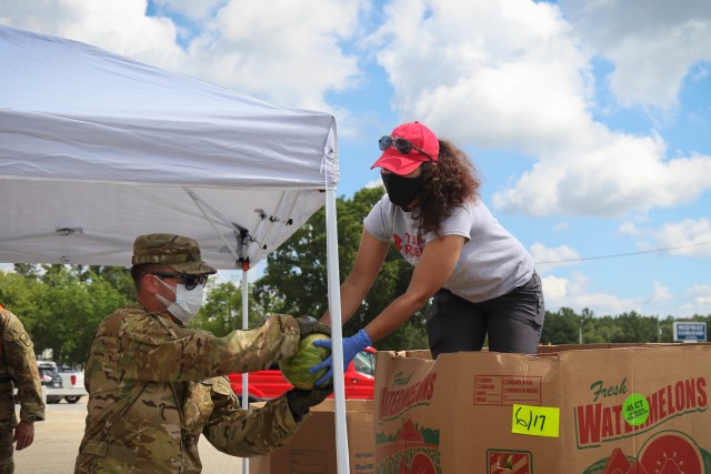 North Carolina Army National Guard Chief Warrant 2 Greg Preston (left) of the 1-130th Attack Reconnaissance Battalion works along side Claudia Suarez, a volunteer for Team Rubicon, a veteran disaster relief service organization, to move produce...