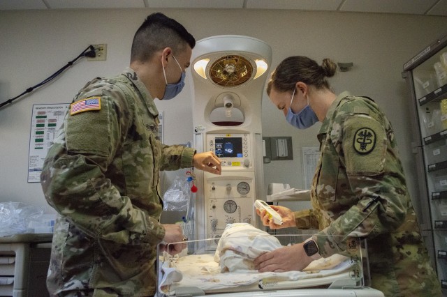 Army Capt. Mateo Betancourt and Army Capt. Elizabeth Koslow simulate checking on a swaddled infant in the Pediatrics ward at Brooke Army Medical Center. Both doctors completed their residency and graduated from the San Antonio Uniformed Services Health Education Consortium in June. (U.S. Army Photo by Daniel J. Calderón)