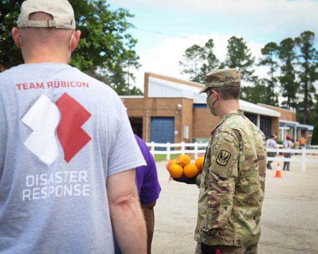 North Carolina Army National Guard Sgt. Timothy Cornell (right), assigned to 2-130th Airfield Operations Battalion, places food into a vehicle while working alongside volunteers from Team Rubicon, a veteran disaster relief service organization, Action Pathways, a non-profit organization, and the Second Harvest Food Bank Southeast to distribute food to approximately 250 families at the Midway Elementary School in Dunn, N.C., June 18, 2020. The NCNG is working with North Carolina Emergency Management, N.C. Department of Health and Human Services and local food banks to help support COVID-19 relief efforts. (North Carolina Army National Guard photo by Spc. Hannah Tarkelly, 382nd Public Affairs Detachment/Released).