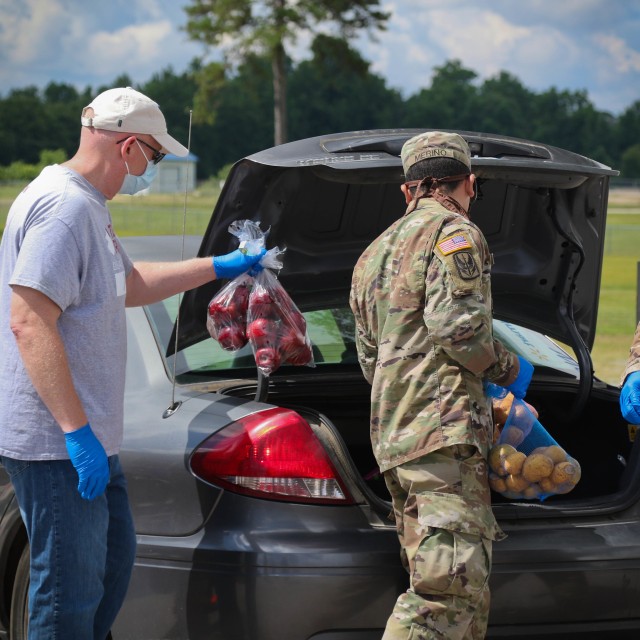 North Carolina Army National Guard Spc. Louis Merino (right), assigned to 2-130th Airfield Operations Battalion, places food in a vehicle alongside Mark Heinlein, a volunteer for Team Rubicon, a veteran disaster relief service organization during the Second Harvest Food Bank Southeast food distribution at the Midway Elementary School in Dunn, N.C., June 18, 2020. The NCNG is working with North Carolina Emergency Management, N.C. Department of Health and Human Services and local food banks to help support COVID-19 relief efforts. (North Carolina Army National Guard photo by Spc. Hannah Tarkelly, 382nd Public Affairs Detachment/Released).