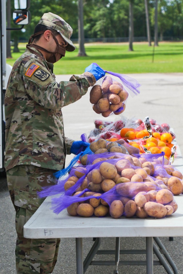 North Carolina Army National Guard Spc. Louis Merino, assigned to 2-130th Airfield Operations Battalion, sorts produce while working alongside volunteers from Team Rubicon, a veteran disaster relief service organization, Action Pathways, a non-profit organization, and the Second Harvest Food Bank Southeast to distribute food to approximately 250 families at the Midway Elementary School in Dunn, N.C., June 18, 2020. The NCNG is working with North Carolina Emergency Management, N.C. Department of Health and Human Services and local food banks to help support COVID-19 relief efforts. (North Carolina Army National Guard photo by Spc. Hannah Tarkelly, 382nd Public Affairs Detachment/Released).