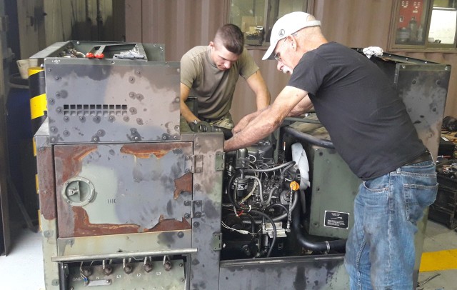 Field Service Representative Gary Dygert installs an engine on a 15 kilowatt generator while working with unit personnel assigned to the Korea peninsula. (U.S. Army photo)