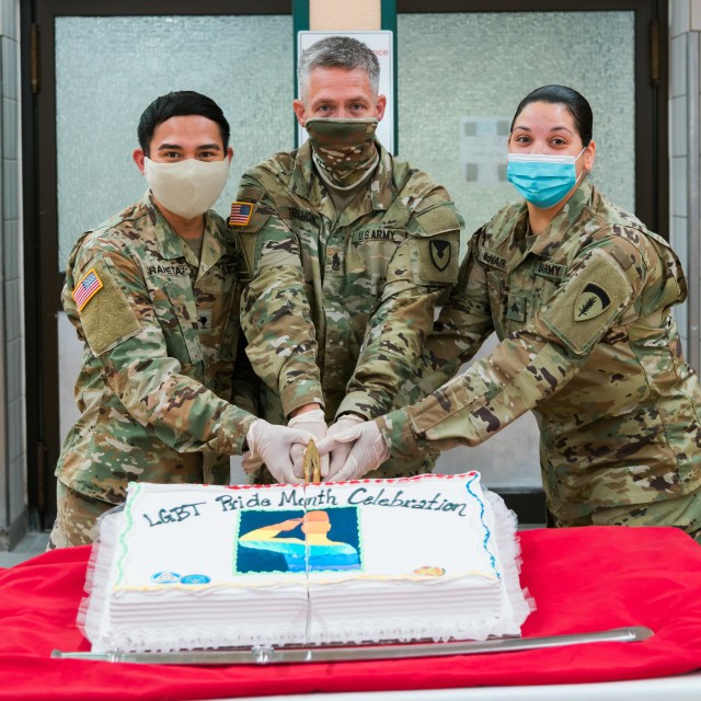 WIESBADEN, Germany -  Spc. Herminigildo Araneta and Sgt. Natahlie McNair assisted Command Sgt. Maj. Christopher Truchon in cutting the Pride Month cake at the Strong Europe Café at U.S. Army Garrison Wiesbaden June 25, 2020.