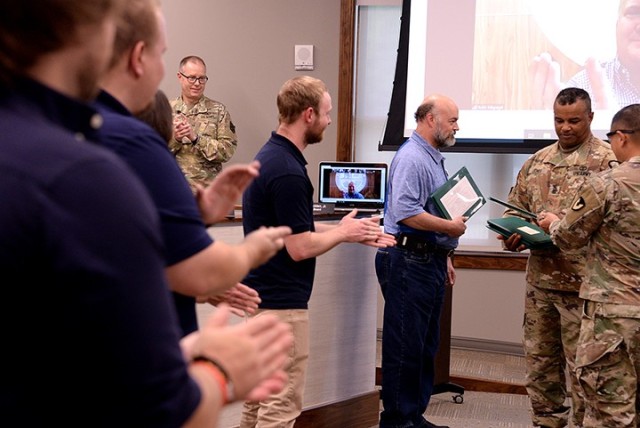 Garrison Commander Col. Harry Hung and Garrison Command Sgt. Maj. Antwone Jones, right, recognize Unified School District 207 personnel who assisted with the broadcast of the Garrison team's triweekly community updates from the district office to...