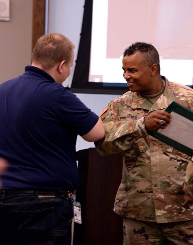 Garrison Command Sgt. Maj. Antwone Jones elbow-bumps Ross Viets, network administrator, while thanking Unified School District 207 personnel for their assistance broadcasting the community updates over the past few months during the USD 207 Board...