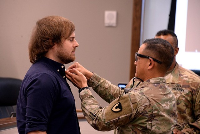 Garrison Commander Col. Harry Hung pins Matt Dixon, technology media specialist, with the Public Service Commendation Medal while recognizing Dixon and other Unified School District 207 personnel for assisting with broadcasting Hung's triweekly...