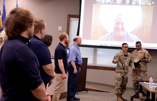 Garrison Commander Col. Harry Hung and Garrison Command Sgt. Maj. Antwone Jones, right, recognize Unified School District 207 personnel who assisted with the broadcast of the Garrison team's triweekly community updates from the district office to...