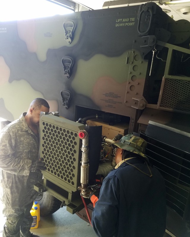 Field Service Representatives Edward Smith, left, and William Jason service generators and environmental control units on Command Post Platform systems in Germany as part of the Depot Maintenance Forward program. (Photo by Jose Marrero)