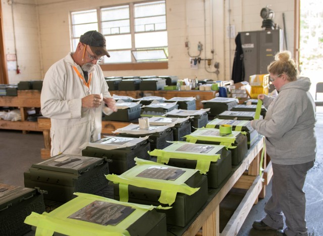 Kent Romine, left, and Vanessa Ward, right, prepare reactive armor tiles for stenciling at Anniston Munitions Center. These tiles, which will go on combat vehicles, have been returned to Code A condition by ANMC employees.