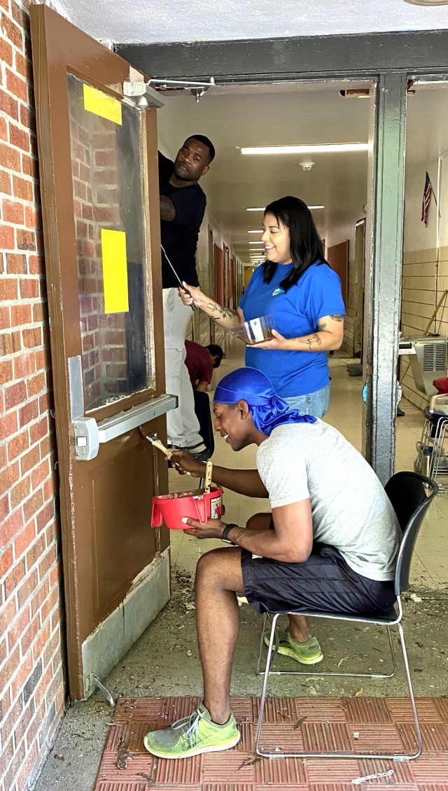 From left to right: Spc. Nalijah Caudle, Cpl. Bianca Ortiz and Spc. Elijah Johnson repaint doors at Vernon Middle School.