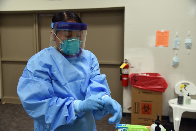 Spc. Paige Curtiss, 253rd Engineer Battalion, food service specialist, puts on personal protection equipment before entering a COVID-19 hot zone at an alternate care facility on the Navajo Nation in Chinle, Ariz., June 2, 2020. Arizona National...