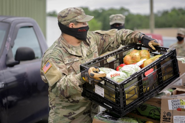 North Carolina Army National Guardsmen Spc. Isai Arroyo, assigned to the 883rd Engineer Company, carries produce to a vehicle during a drive-up food bank hosted by the Second Harvest Food Bank of Northwest North Carolina in a warehouse in...