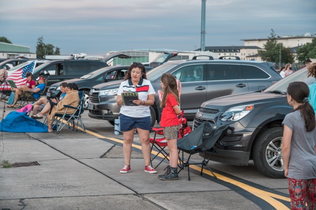 WIESBADEN, Germany - Jane Porto-Turner, advertising and sponsorship manager for MWR, conducts a trivia contest with a young spectator July 4, 2020, at Wiesbaden Army Airfield. MWR hosted a live feed of the event.