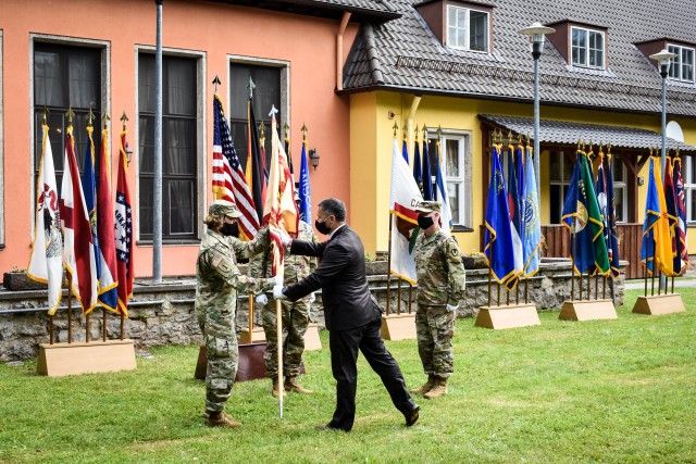 Tommy R. Mize, Installation Management Command-Europe Director, passes the colors to Col. Karen E. Hobart during the change of command ceremony at the Von Steuben Community Center on Bismarck Kaserne July 8.