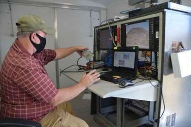 Johnny Gallegos, DPG Scientific Technical Photographer, wears a mask as he checks the monitors displaying the view from several cameras set to capture the launch and detonation of an innovative missile system recently tested at DPG. Photo by Becki Bryant, Dugway Public Affairs