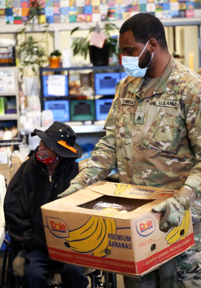 Sgt. Nikko Ethridge, a cavalry scout with 1st Battalion, 161st Infantry Regiment helps a visitor at the St. Leo's Food Bank in Tacoma. To date the Guard has helped process, pack and distribute more than 35 million pounds of food. (U.S. National Guard photo by Joseph Siemandel)