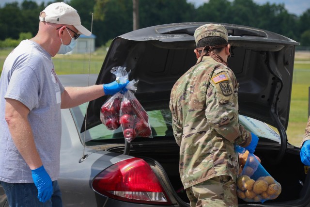 North Carolina Army National Guard Spc. Louis Merino (right), assigned to 2-130th Airfield Operations Battalion, places food in a vehicle alongside Mark Heinlein, a volunteer for Team Rubicon, a veteran disaster relief service organization during the Second Harvest Food Bank Southeast food distribution at the Midway Elementary School in Dunn, N.C., June 18, 2020. The NCNG is working with North Carolina Emergency Management, N.C. Department of Health and Human Services and local food banks to help support COVID-19 relief efforts. 