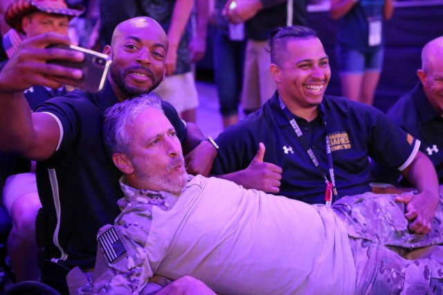 U.S. Army veterans Brent Garlic and Joel Rodriguez take a selfie with Jon Stewart during the DoD Warrior Games opening ceremony, June 22, 2019, at Amalie Arena during the 2019 Department of Defense Warrior Games. The DoD Warrior Games are...