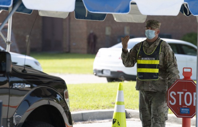 Sgt. 1st Class Phillip Aaron StPierrre, with Company B, Headquarters and Headquarters Battalion, waves a car forward during drive up COVID-19 testing July 10.