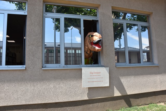 WIESBADEN, Germany – An inflatable dinosaur grabs the attention of passers by the Wiesbaden Library as it hangs its head out the window July 14, 2020 (U.S. Army Photo by Emily Jennings).