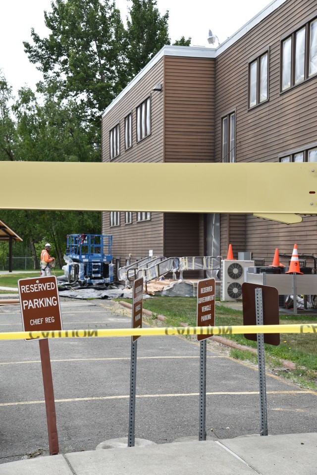 Equipment sits near the building as workers prepare the northeast side for primer and paint. The crew advanced counterclockwise around the building, finishing the work in sections as the new colors became visible to the district.