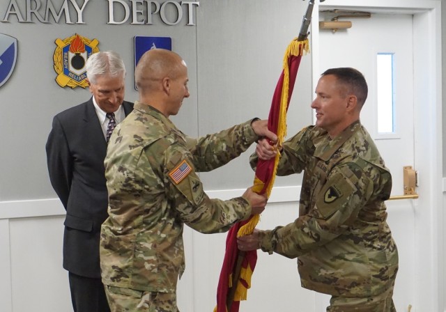 Col. Steven Dowgielewicz (left) grabs unit colors symbolically assuming command of Tooele Army Depot from Col. Todd Burnley (right).