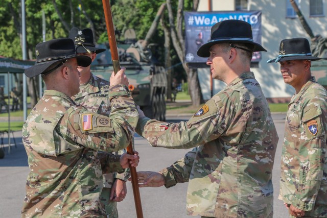 U.S. Army Command Sgt. Maj. Marcus Brister, assigned to 3rd Squadron, 2nd Cavalry Regiment, passes a guidon to Lt. Col. Andrew Gallo, the outgoing Battle Group Poland commander during a change of command ceremony in Bemowo Piskie Training Area, Poland, July 17, 2020. Gallo relinquished his command of the battle group to Lt. Col. Jeffery Higgins, assigned to 2nd Squadron, 2nd Cavalry Regiment. (U.S. Army photo by Cpl. Justin W. Stafford)