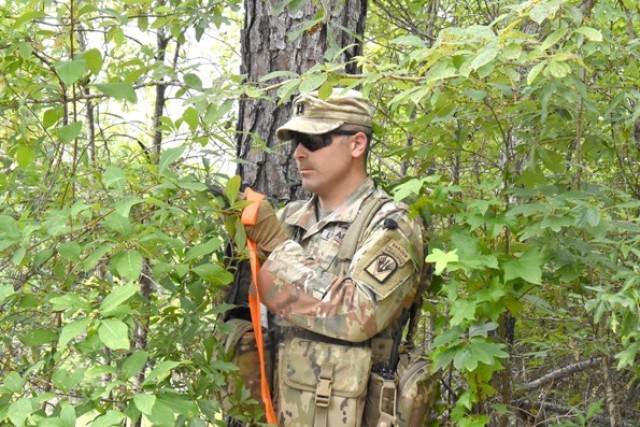 Capt. Aaron Scherffius, JRTC Operations Group Task Force 5, uses a compass to determine the angle for felling a tree to build an abatis.