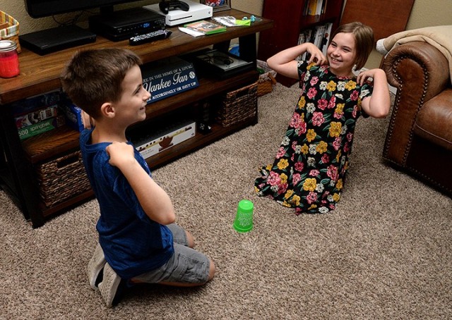 Nine-year-old twins Timothy and Victoria Kallo listen to their father call "head" and "shoulders" until finally announcing "cup" to try to be the first to grab the cup during Vacation Bible School July 21 at their on-post home. VBS was offered...