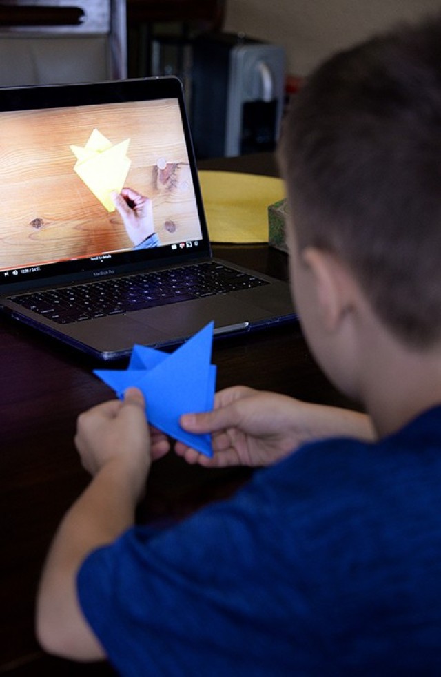 Nine-year-old Timothy Kallo watches origami instruction to fold a paper flower during virtual Vacation Bible School July 21 at his on-post home. Due to ongoing COVID-19 precautions, VBS was offered virtually this year in an online video curriculum...