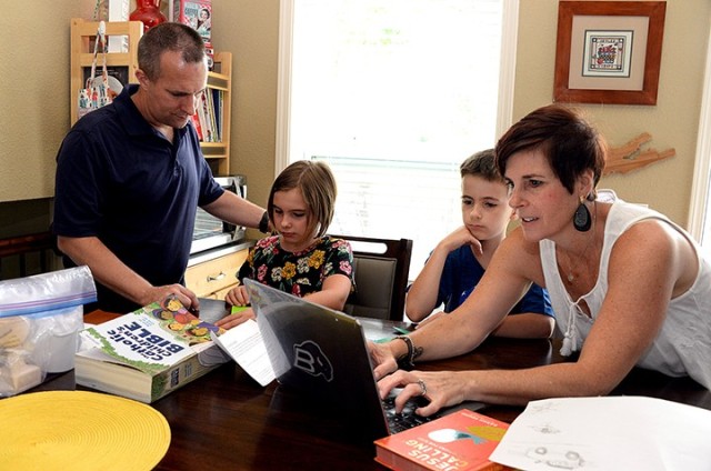 Lt. Col. John Kallo, Mission Command Center of Excellence, watches 9-year-old Victoria fold an origami flower as 9-year-old Timothy watches Nicole Kallo get the family back online after losing the virtual Vacation Bible School feed for a second...