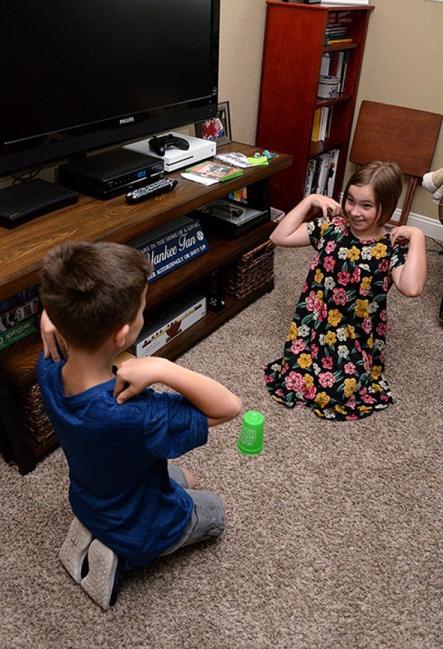 Nine-year-old twins Timothy and Victoria Kallo listen to their father call "head" and "shoulders" until finally announcing "cup" to try to be the first to grab the cup during Vacation Bible School July 21 at their on-post home. VBS was offered...