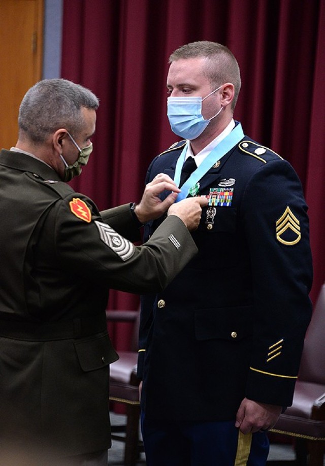 After draping the Sergeant Audie Murphy Club medallion around Staff Sgt. Paul Michaud’s neck, Combined Arms Center Command Sgt. Maj. Eric Dostie pins him with the Army Commendation Medal during the SAMC induction ceremony July 22 in Grant...