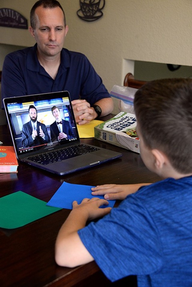 Lt. Col. John Kallo, Mission Command Center of Excellence, watches his 9-year-old son, Timothy, participate in Vacation Bible School via online curriculum, complete with origami crafts and games, July 21 at their on-post home. Instructions to fold...