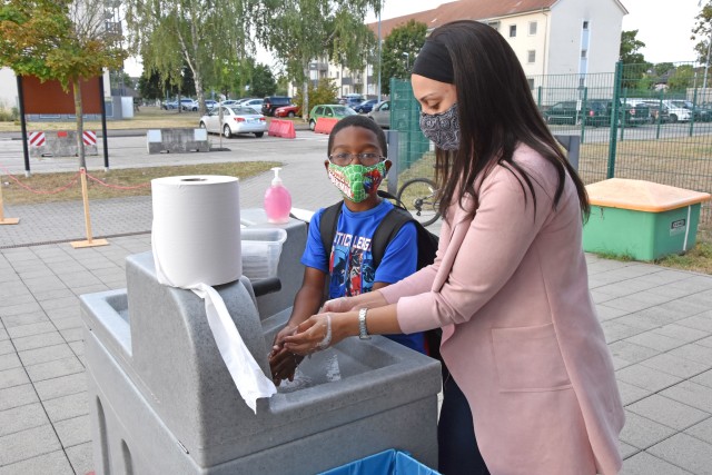 WIESBADEN, Germany - Sydne Tansiel washes her hands with son Travis Jr. before dropping him off at the Child Development Center July 24 on Clay Kaserne. CDCs at U.S. Army Garrison Wiesbaden have implemented safety measures as they provide care to...