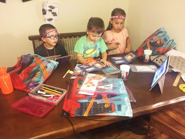 Norman Malinowski (left), 6, his brother, Edmond (center), 4, and sister, Beatrix, 8, work on crafts while watching the Fort Polk Main Post Chapel hybrid vacation bible school lesson online.