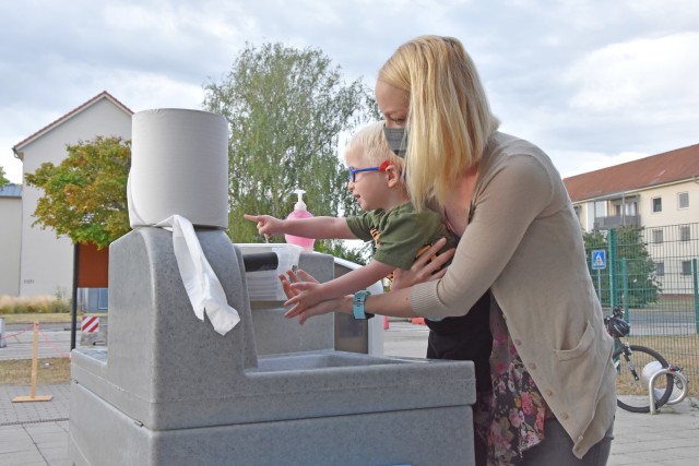 WIESBADEN, Germany - Laura Johnson helps her son Abel wash his hands before dropping him off at the Child Development Center July 24 on Clay Kaserne. CDCs at U.S. Army Garrison Wiesbaden have implemented safety measures as they provide care to the...