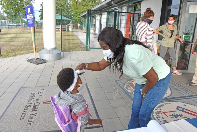 WIESBADEN, Germany - Hazel Ann Swan, supervisory program specialist at the Child Development Center, takes a child’s temperature July 24 during morning drop off. CDCs at U.S. Army Garrison Wiesbaden have implemented safety measures as they...