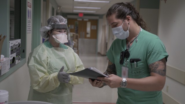 Cesar De La Vega, right, ensures Maj. Kay Bolin properly dons her personal protective equipment in an intensive care unit at Brooke Army Medical Center. (U.S. Army photo by James Camillocci)